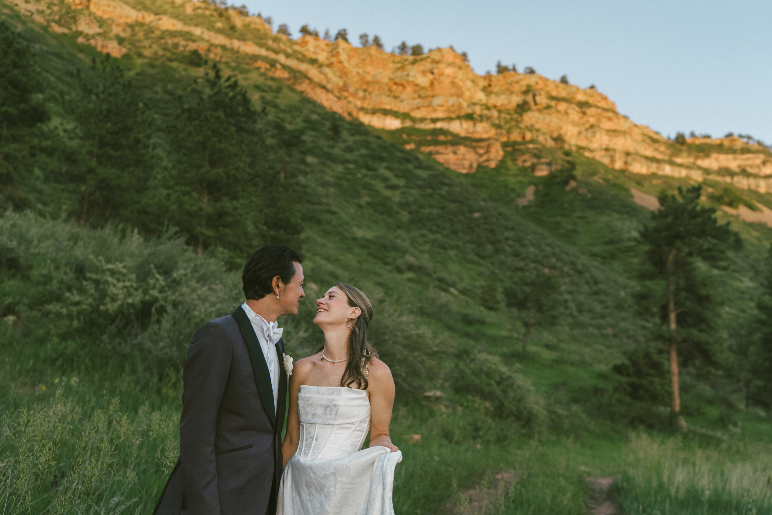 Wedding couple stands in front of Colorado cliffside during a summer wedding