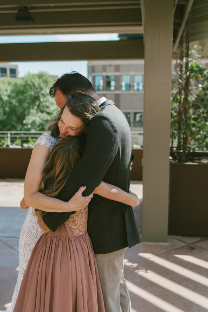 Documentary style wedding photography of wedding couple embracing their 10 year old child.