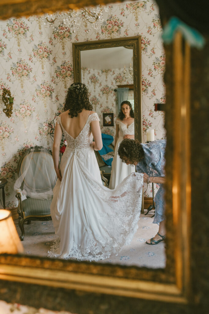 A bride's mother fluffing the train of her wedding dress taken by a documentary style wedding photographer
