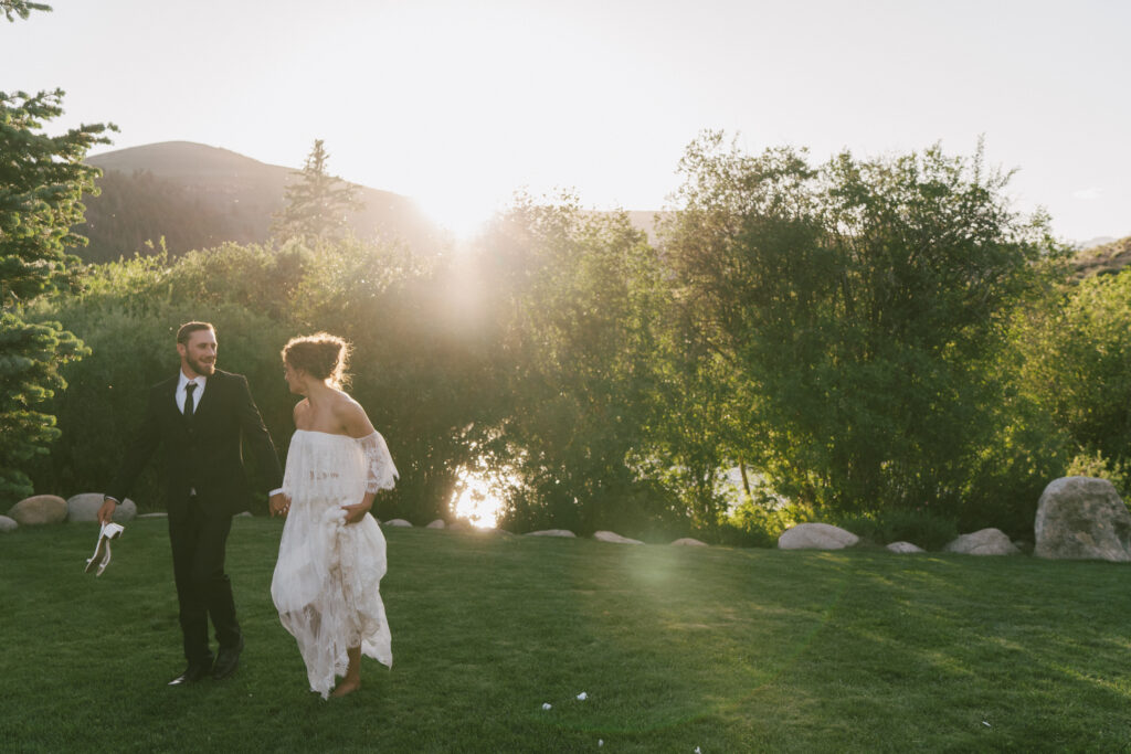A couple walks hand in hand in the late-afternoon light during their summer wedding in Gunnison, CO.