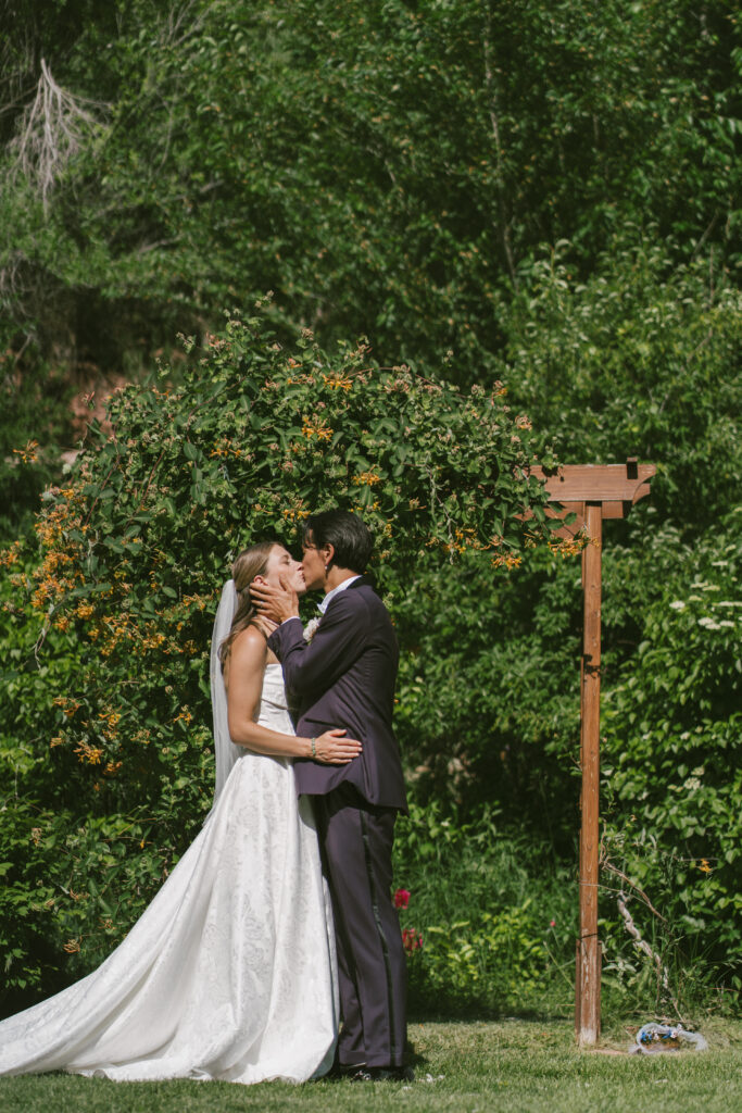 Bride and groom embrace in their first kiss during their June wedding in Colorado.