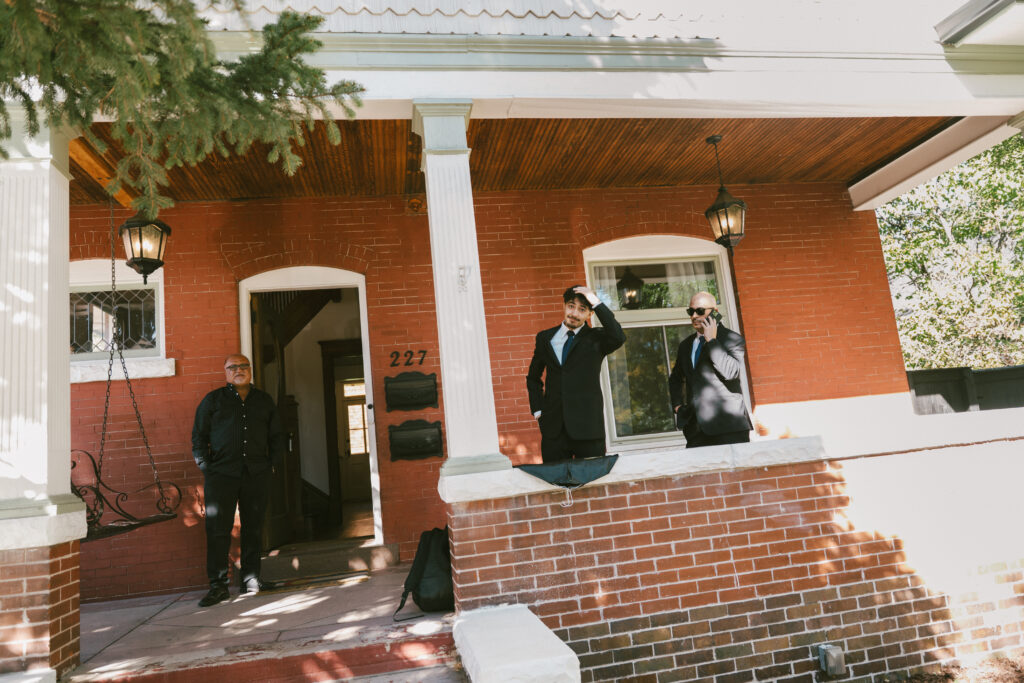 Groomsmen stand outside a house during an October wedding in Denver, CO.